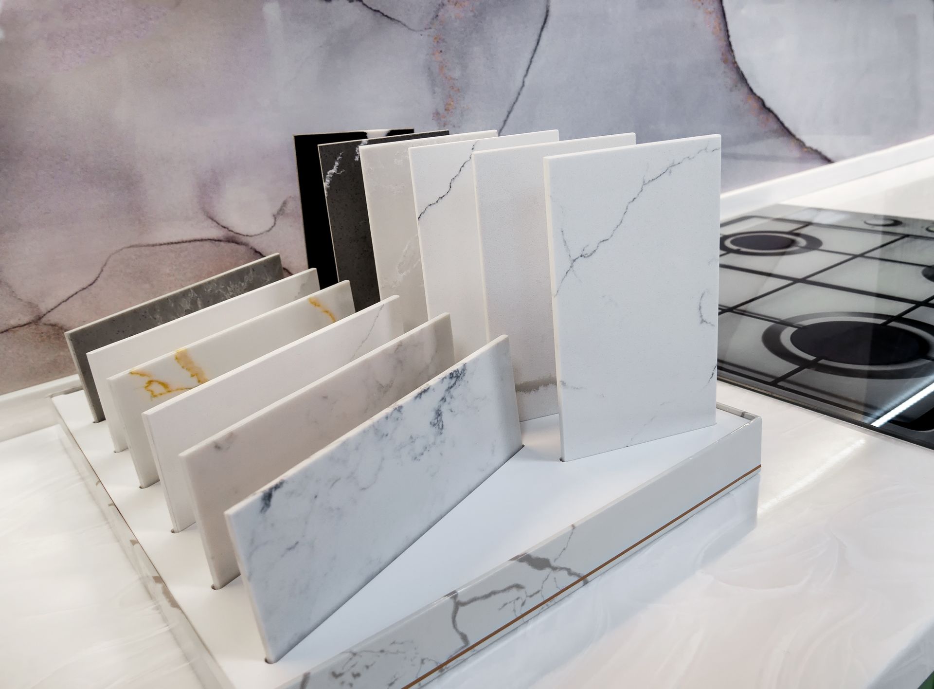 Samples of kitchen countertop materials in various colors and patterns displayed on a shelf.