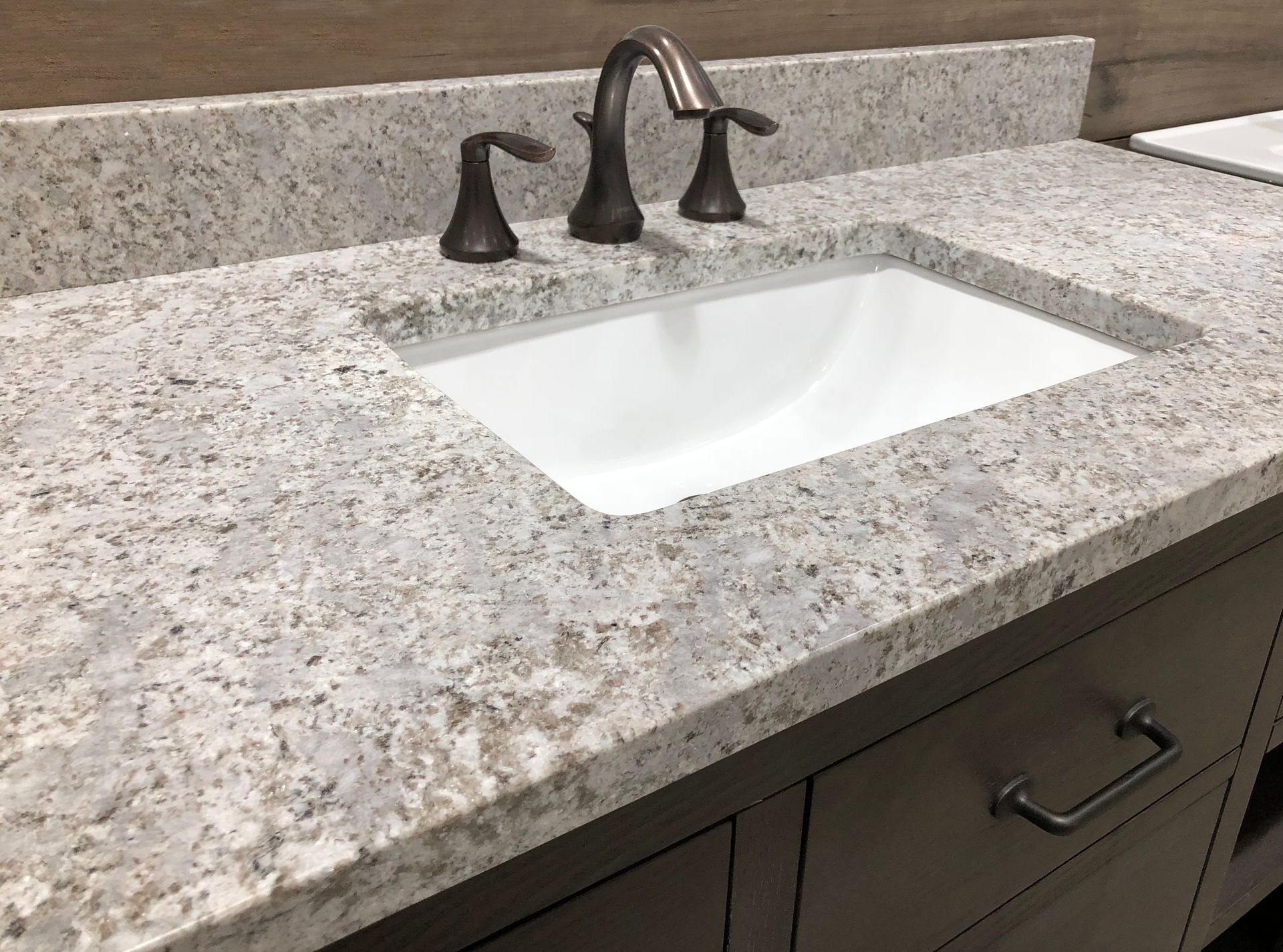 A bathroom sink with a granite counter top and a faucet