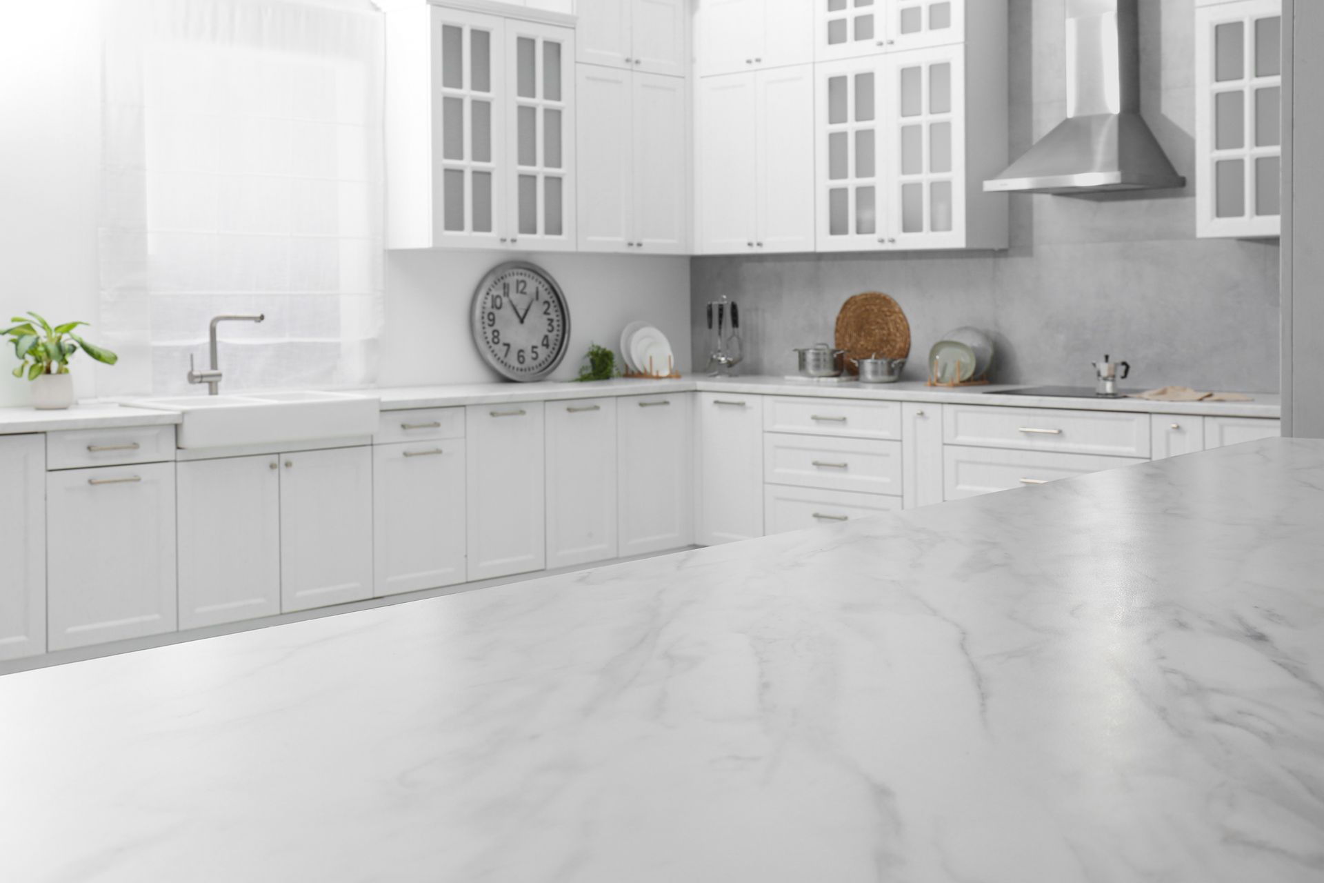 A kitchen with white cabinets and a marble counter top.