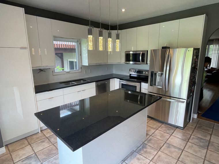 A kitchen with stainless steel appliances and a large island in the middle.