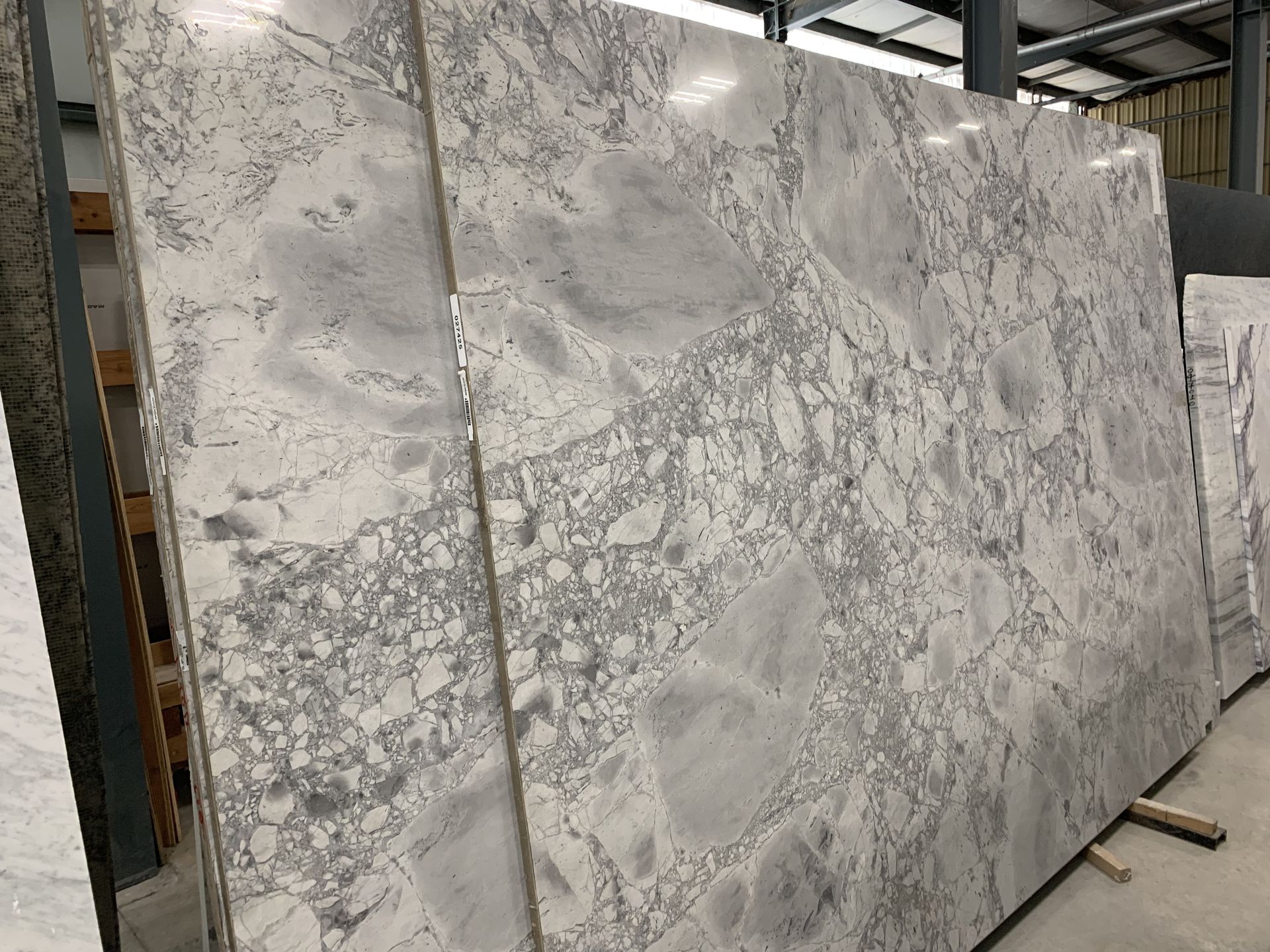 Large slabs of white and gray marble with intricate veining, stacked in a warehouse.