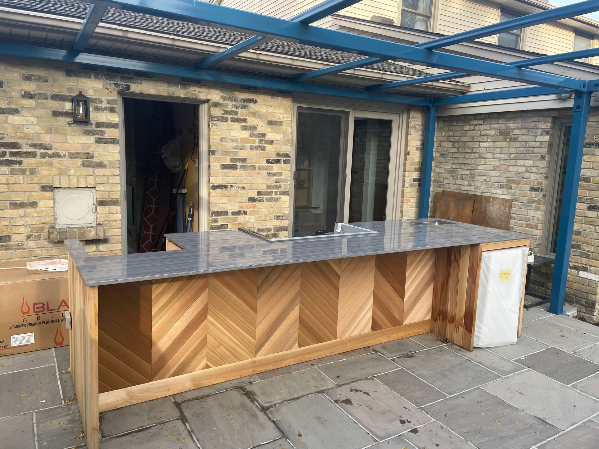 A wooden counter with a marble top is sitting in front of a brick building.