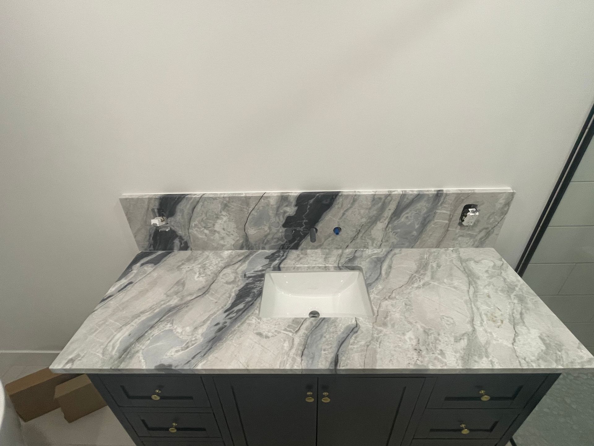 A bathroom vanity with a marble counter top and a sink.