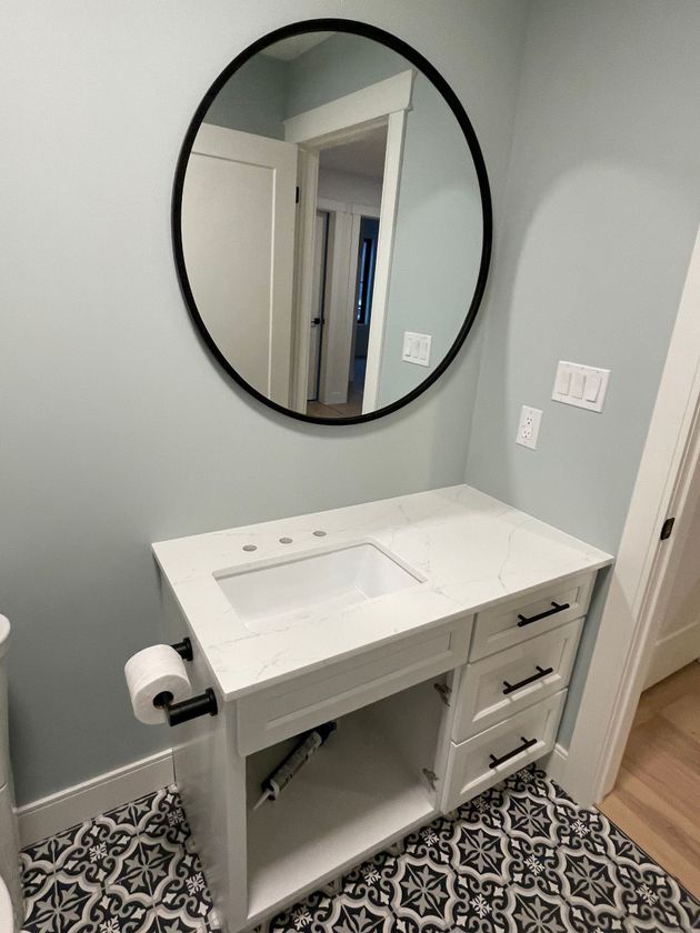 A bathroom with a sink , mirror and toilet paper.