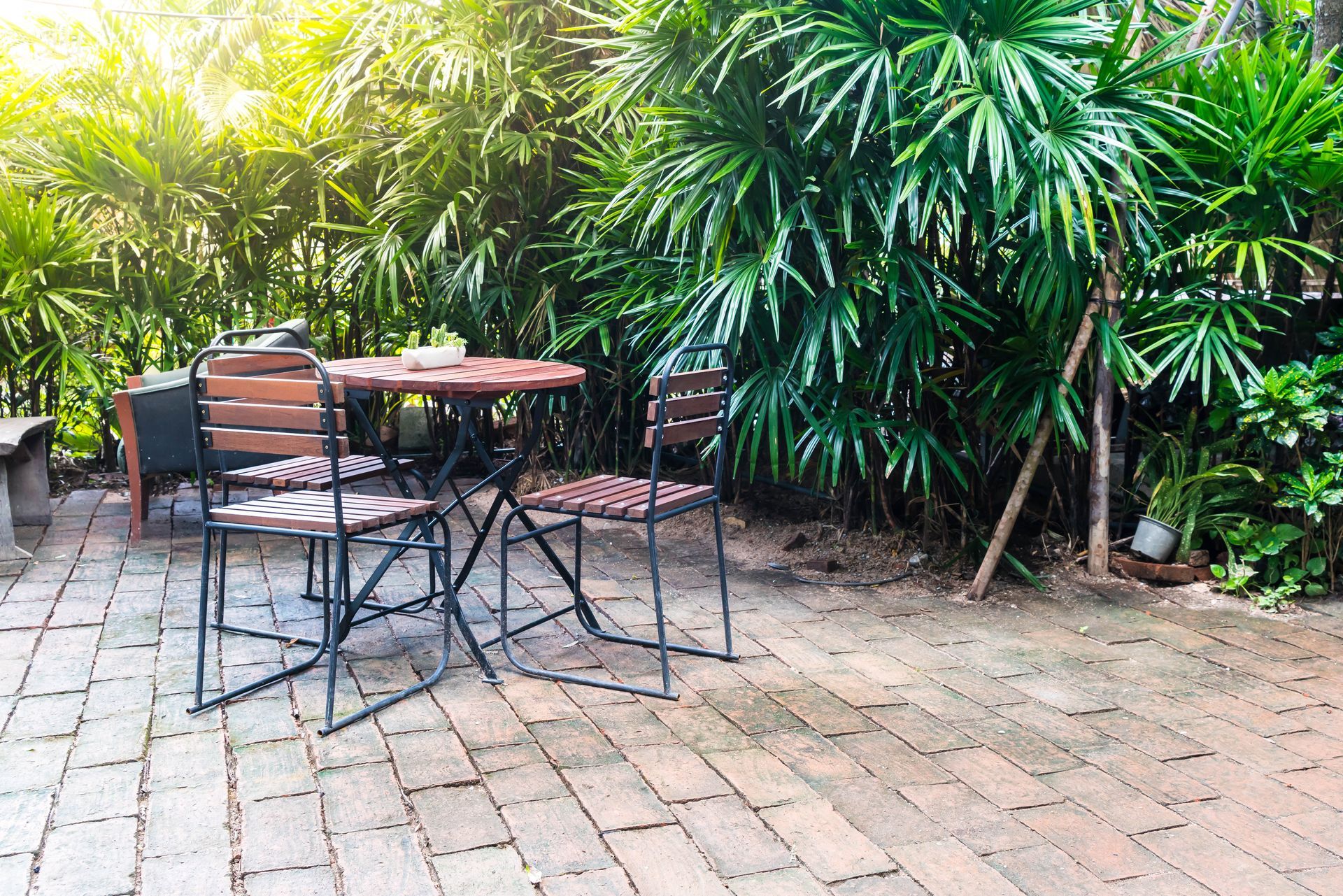 A table and chairs are sitting on a brick patio in a garden.