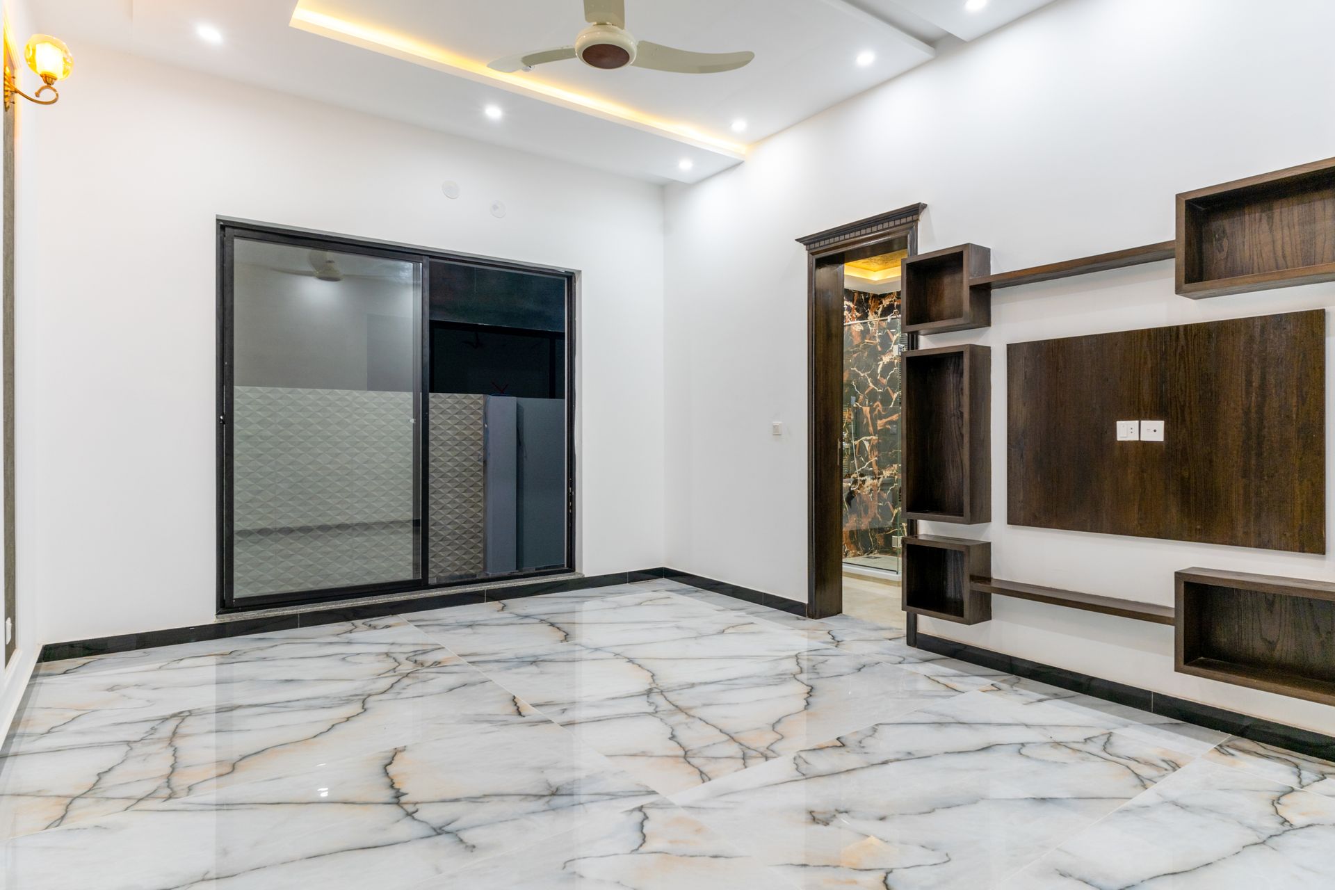 An empty living room with a marble floor and a ceiling fan.