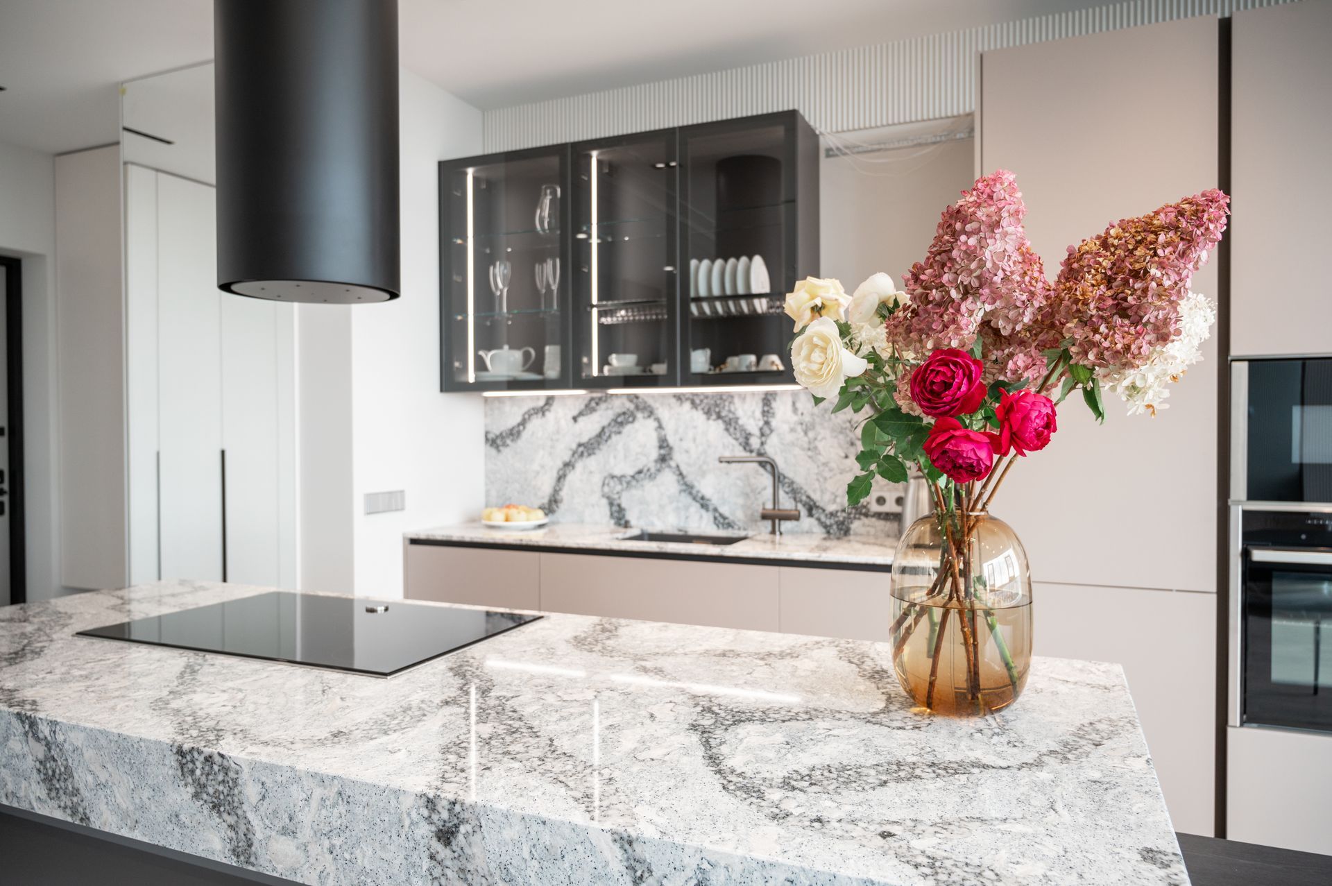 A kitchen with a vase of flowers on the counter.