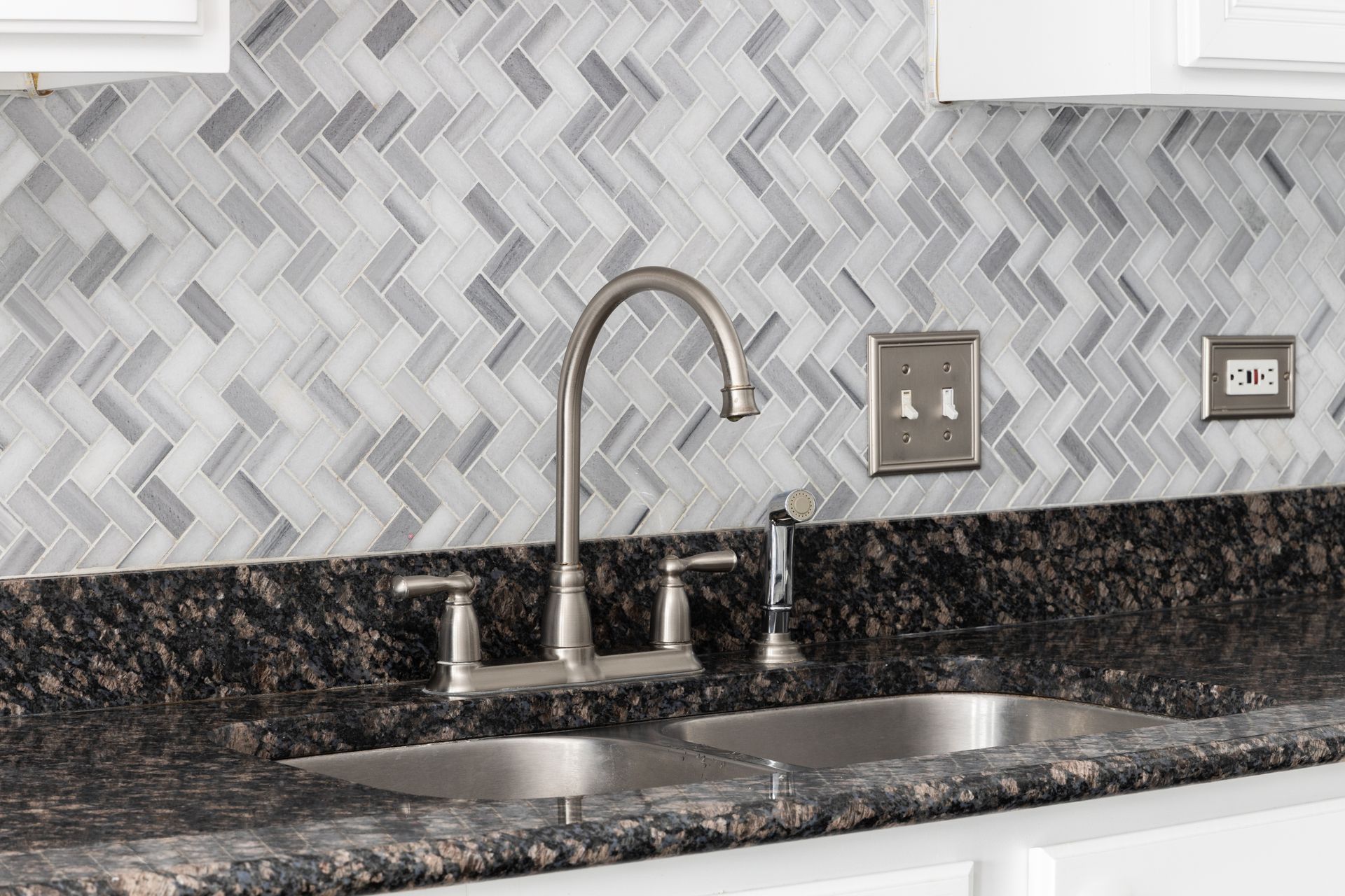 A kitchen sink with a stainless steel faucet and a marble counter top.