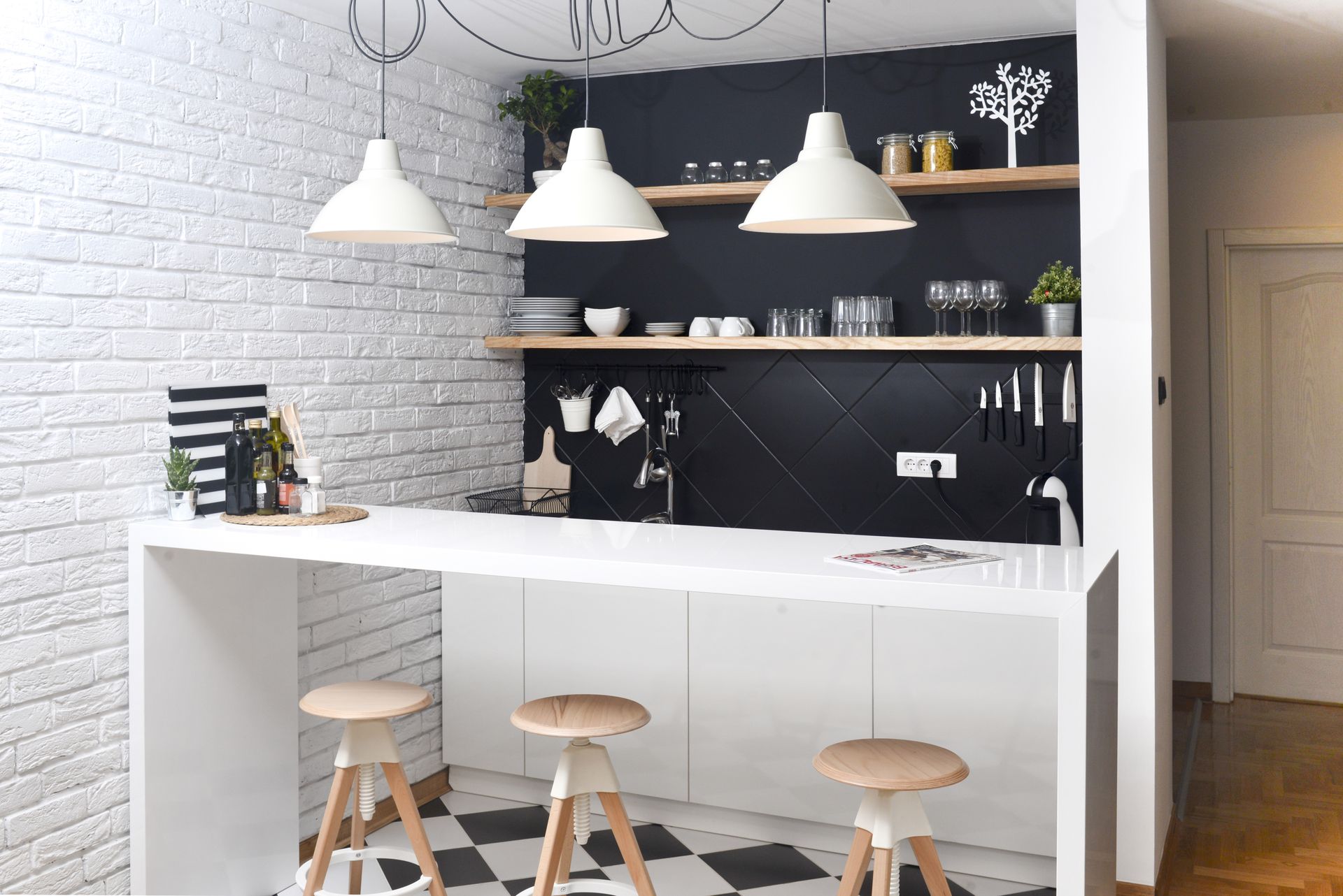 A kitchen with a black and white checkered floor and stools.