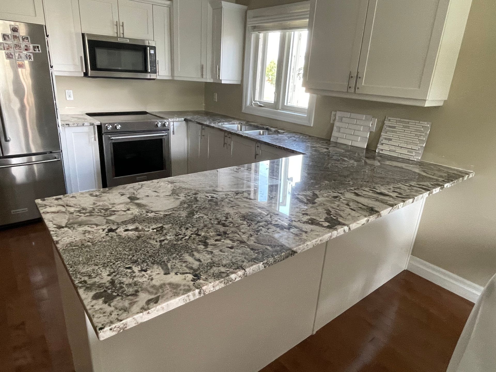 A kitchen with granite counter tops , stainless steel appliances , and white cabinets.