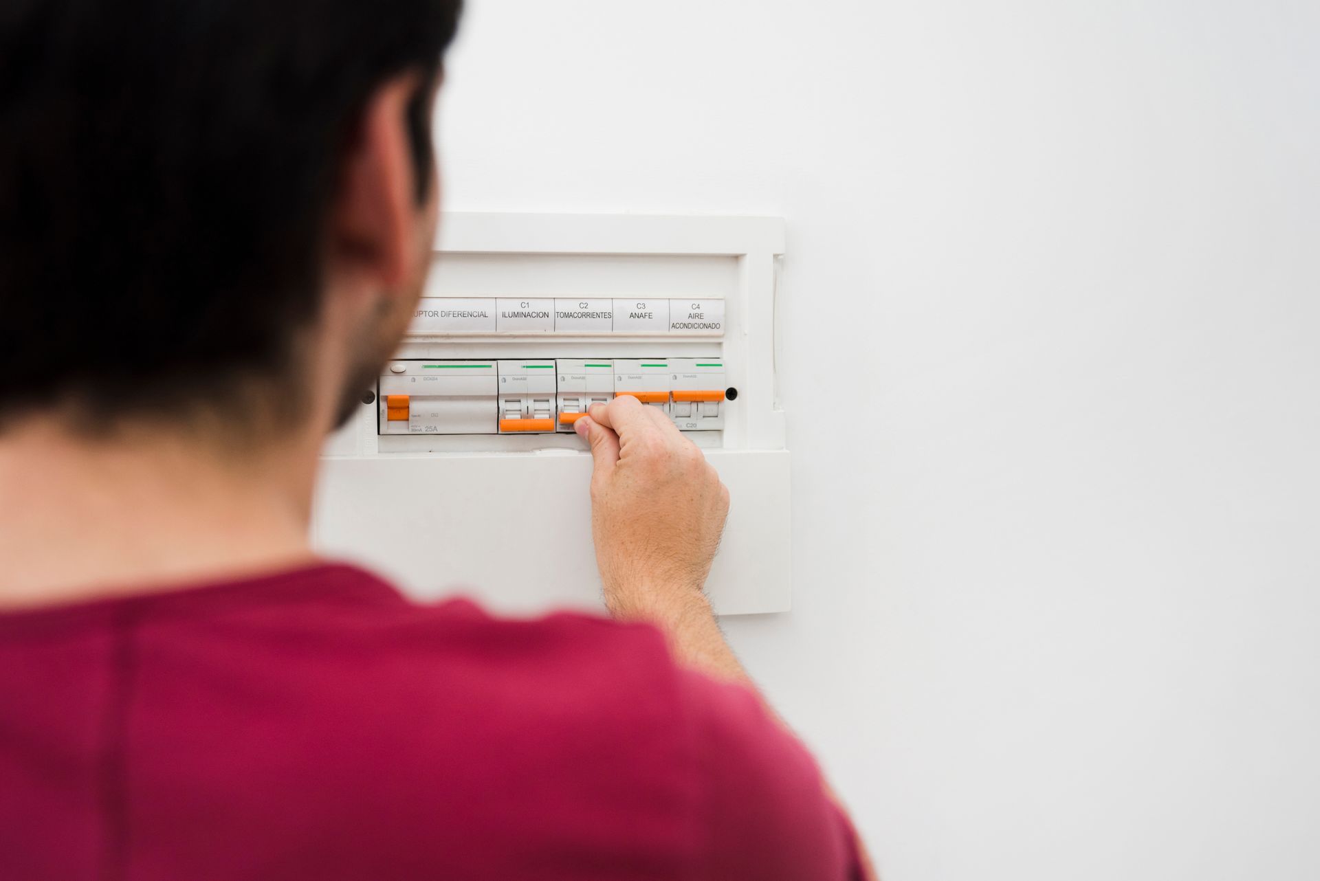 A man is looking at an electrical box on a wall.