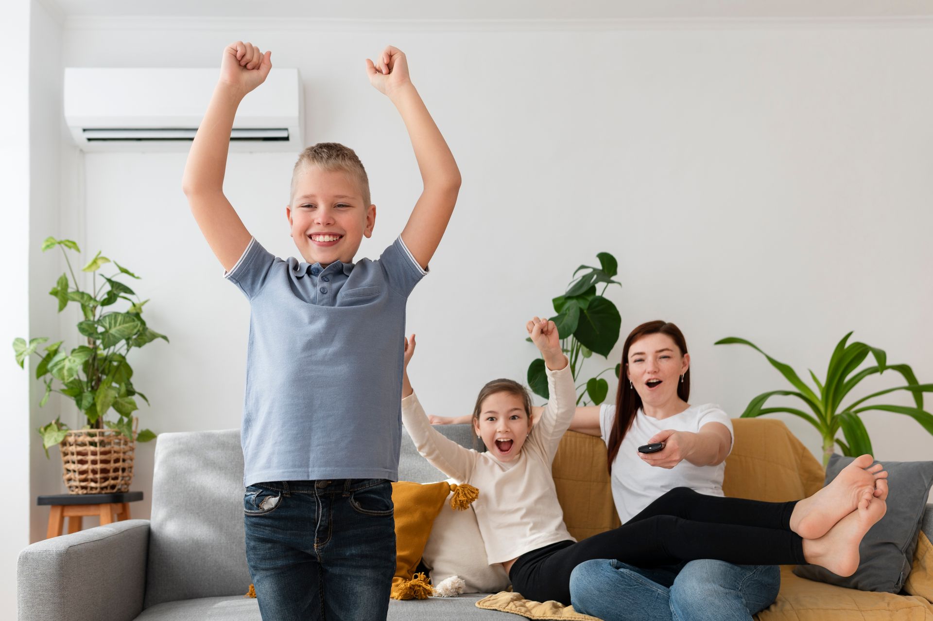 Family cheering on a couch in a bright living room, arms raised with smiling faces