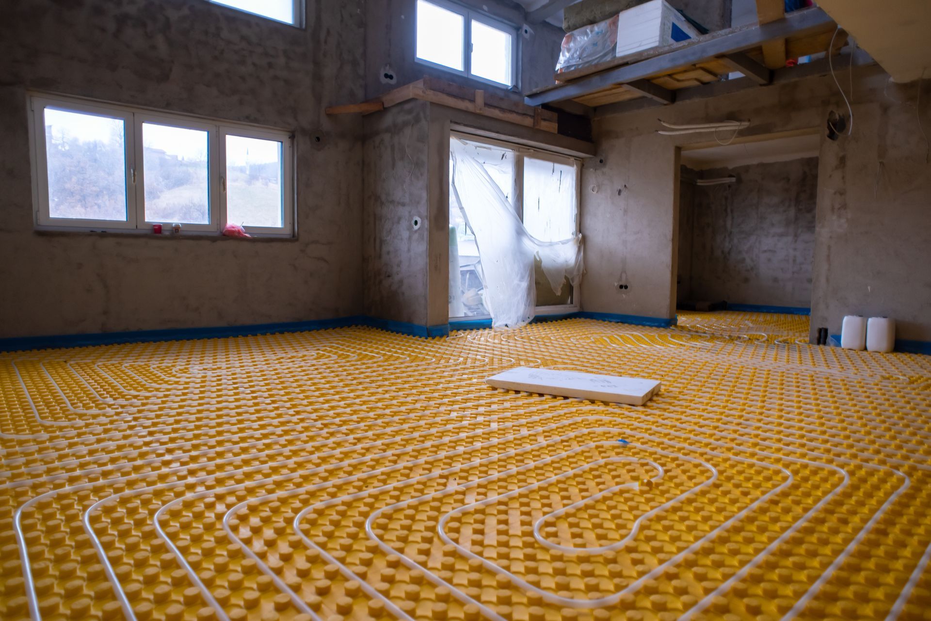 A room under construction with a yellow underfloor heating system.
