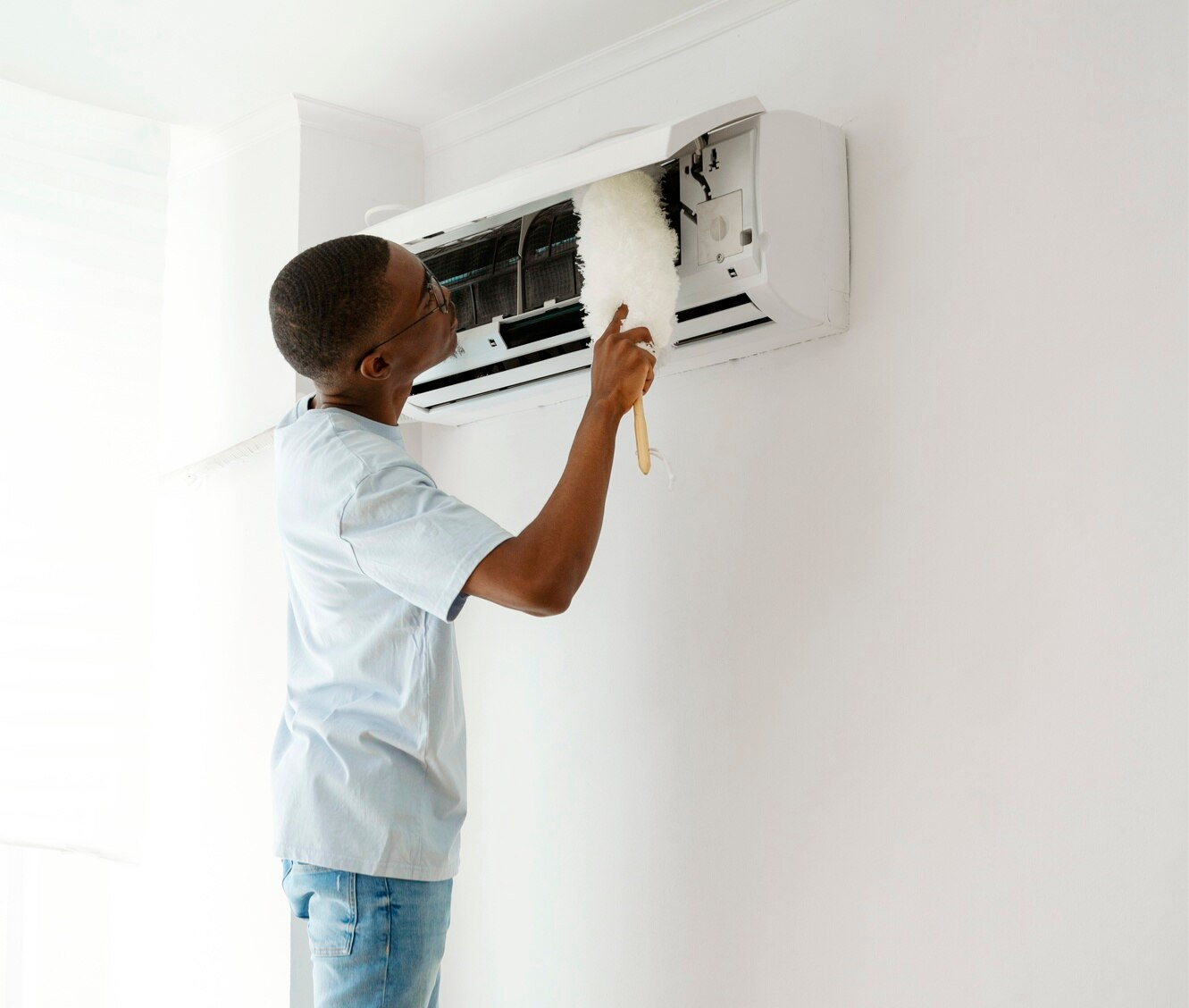 A man is cleaning an air conditioner in a living room.