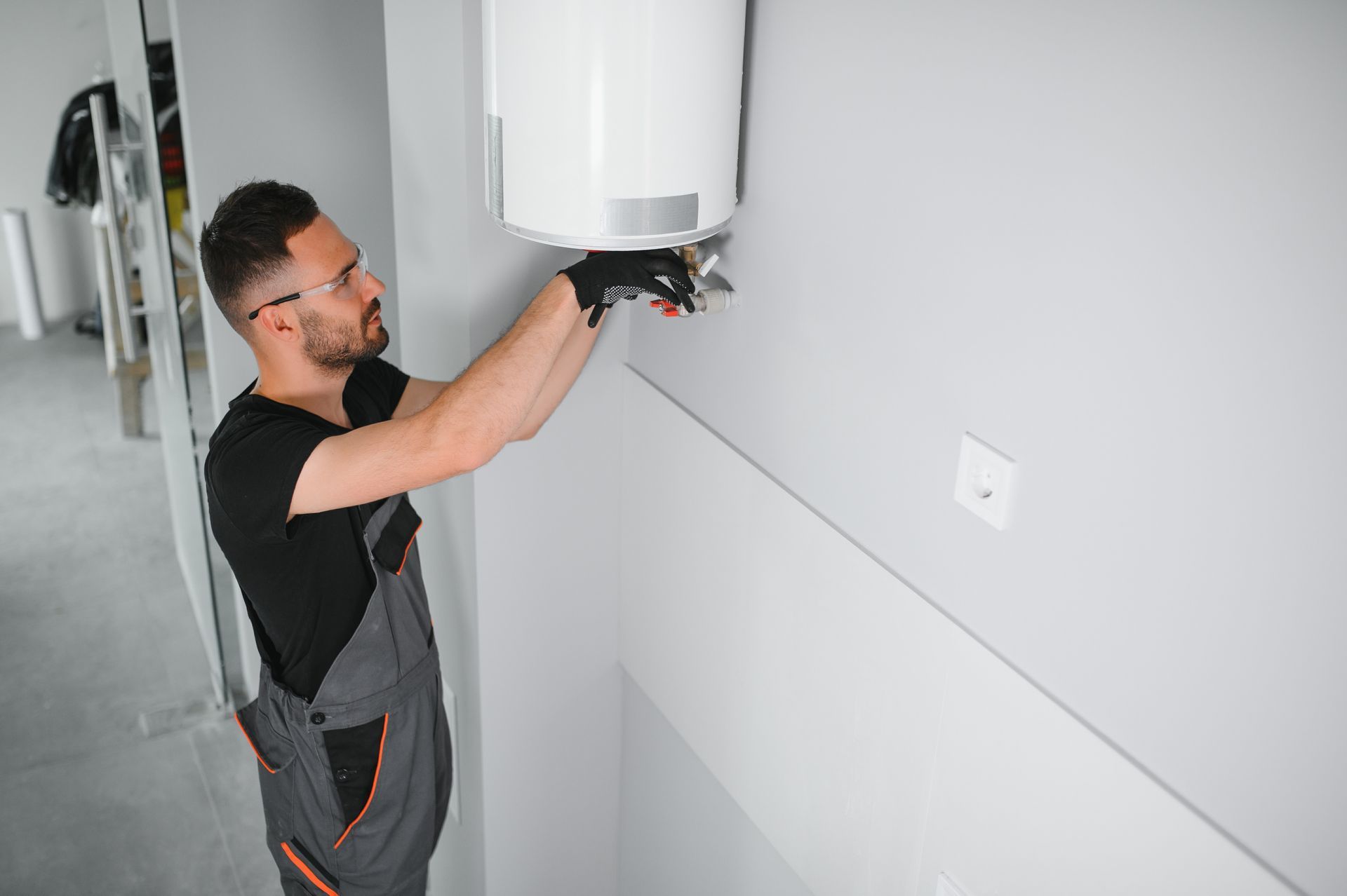 A man is installing a water heater on a wall.