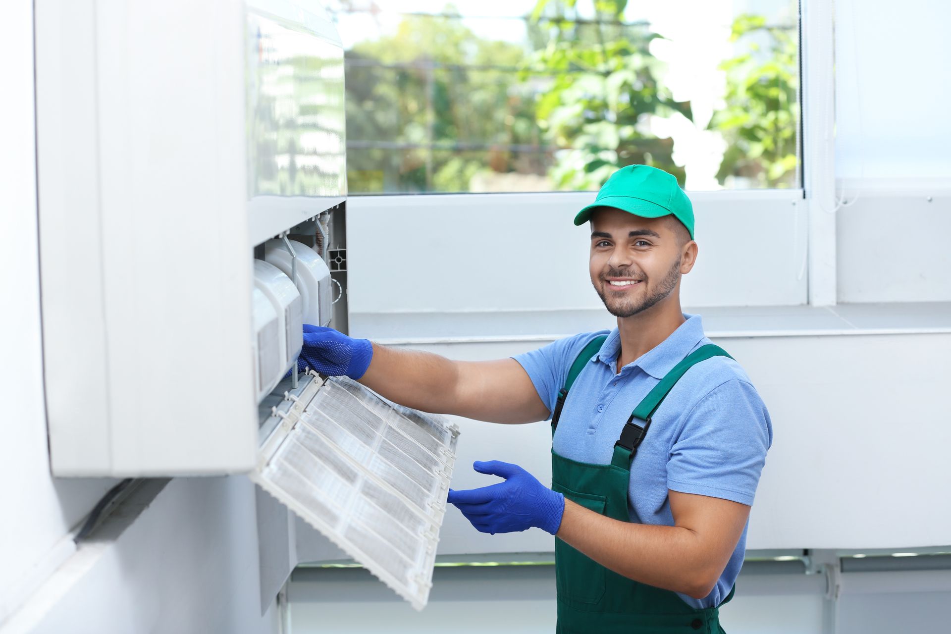 A man is cleaning an air conditioner in a room.
