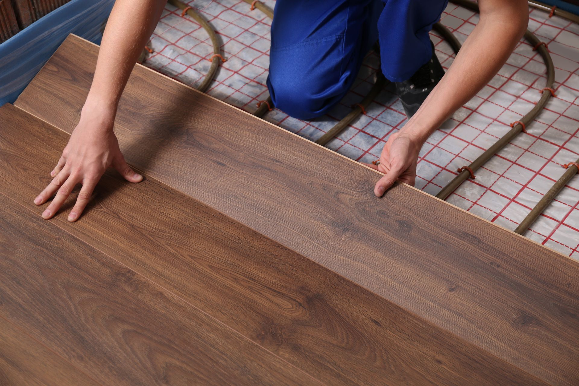 A man is installing a wooden floor in a room.