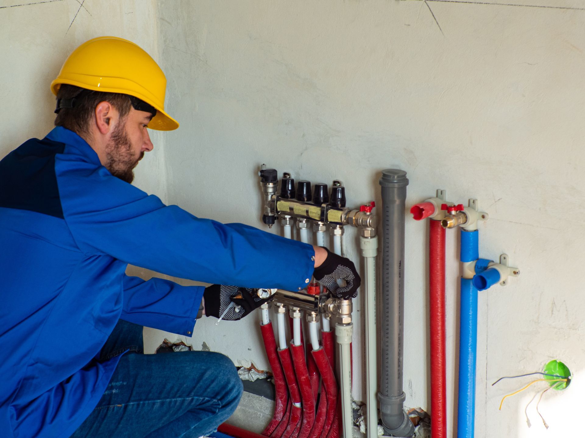 A man wearing a hard hat is working on a pipe system.