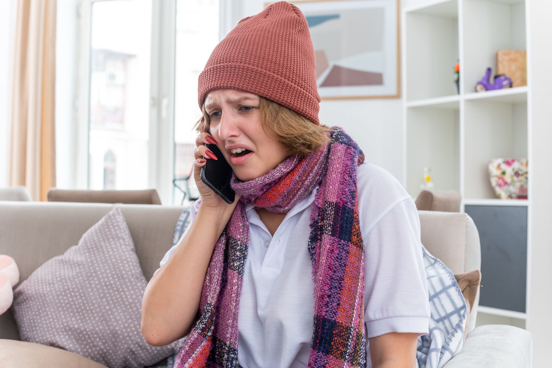A woman is sitting on a couch talking on a cell phone.