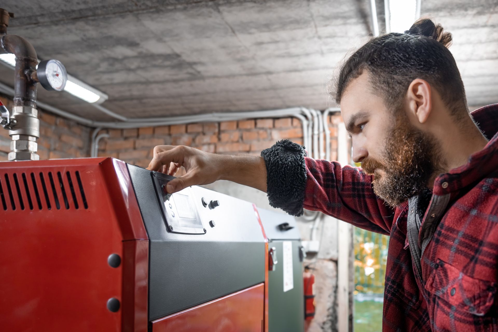 A man is working on a boiler in a garage.