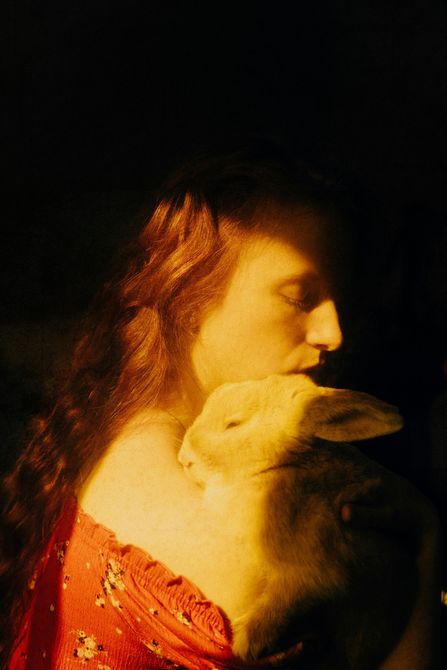 A woman is holding a rabbit in her arms in a dark room.