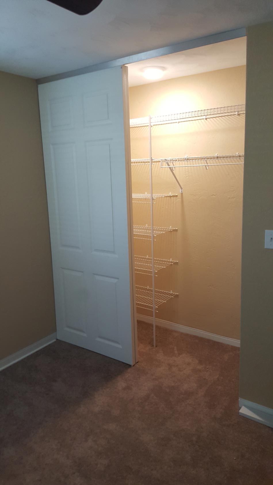 A walk in closet with a sliding door and shelves in a bedroom.