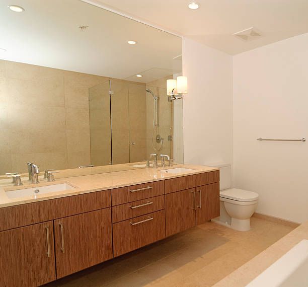 A bathroom with two sinks a toilet and a large mirror