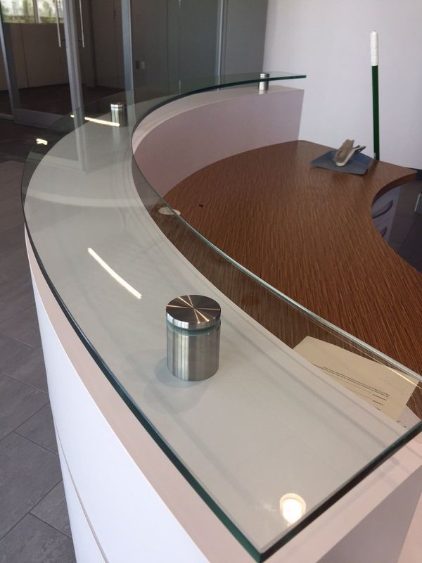 A curved glass counter top with a stainless steel holder
