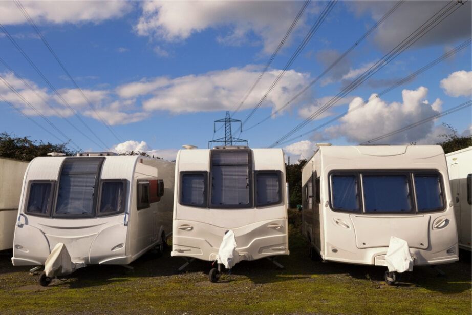 Three White Caravans Parked on Grass Under a Blue Sky with Power Lines — Allchin Airconditioning & Refrigeration Electrical in Caloundra, QLD