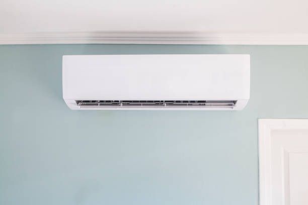 White Ductless Air Conditioner Unit on A Light Blue Wall, Near a Door — Allchin Airconditioning & Refrigeration Electrical in Caloundra, QLD