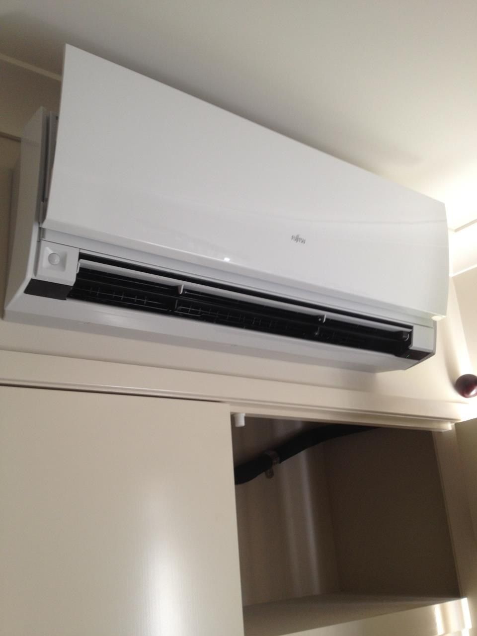 White Fujitsu Air Conditioner Mounted Above a Cabinet — Allchin Airconditioning & Refrigeration Electrical in Caloundra, QLD