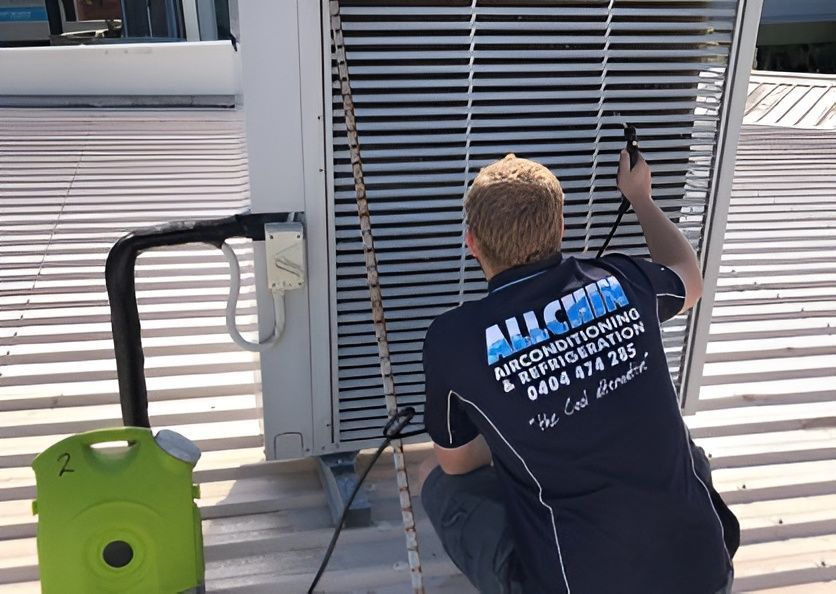 A Man Is Fixing an Air Conditioner — Allchin Airconditioning & Refrigeration Electrical In Caloundra, QLD