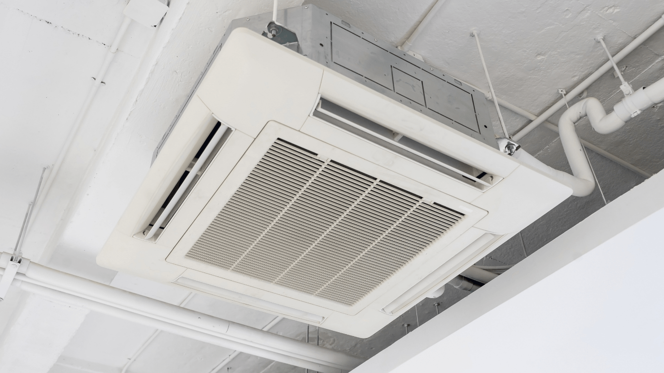 White ceiling-mounted air conditioning unit with a rectangular vent, pipes and ceiling in a bright room — Allchin Airconditioning & Refrigeration Electrical in Caloundra, QLD