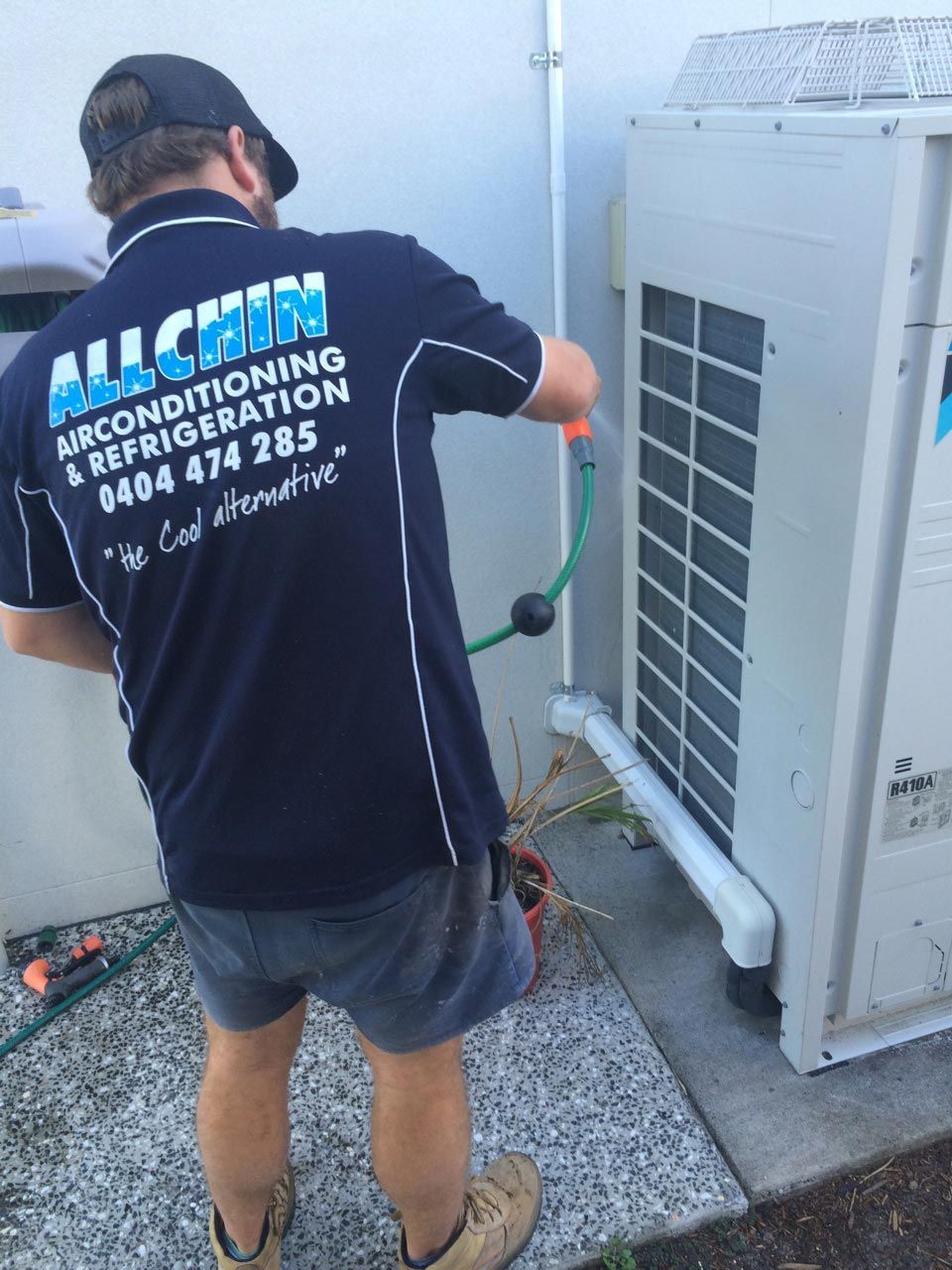 A Man Cleaning the Back Refrigeration — Allchin Airconditioning & Refrigeration Electrical in Caloundra, QLD