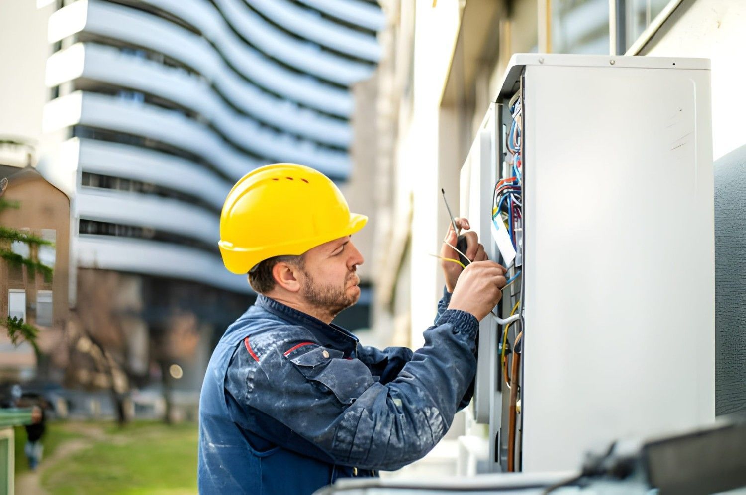 A Man Works on An Electrical Panel Outside a Building — Allchin Airconditioning & Refrigeration Electrical In Caloundra, QLD