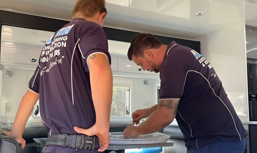 Two Men In Blue Work Shirts Installing Something Inside A Caravan — Allchin Airconditioning & Refrigeration Electrical in Caloundra, QLD