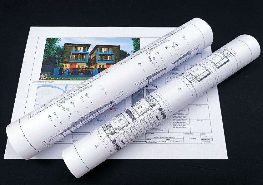 Architectural blueprints rolled up, with one sheet showing a building rendering.