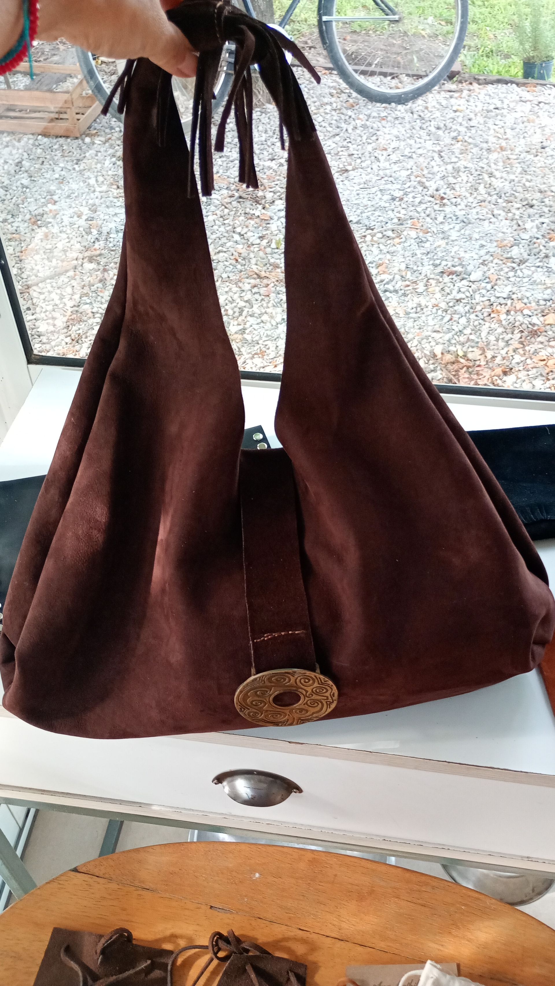 Bolso de hombro de ante marrón con asas largas y hebilla decorativa.