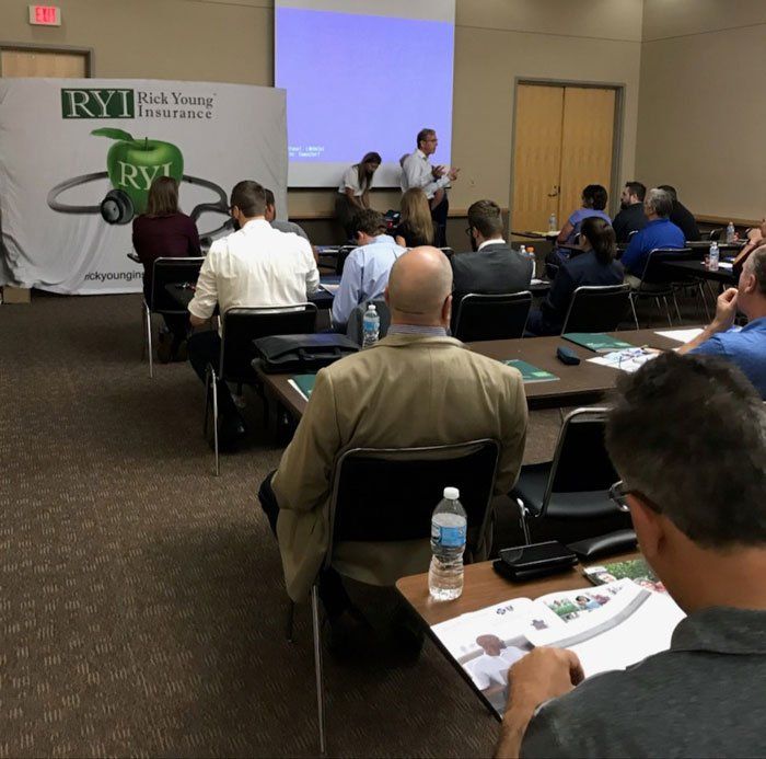 A group of people are sitting at tables in front of a sign that says ryu