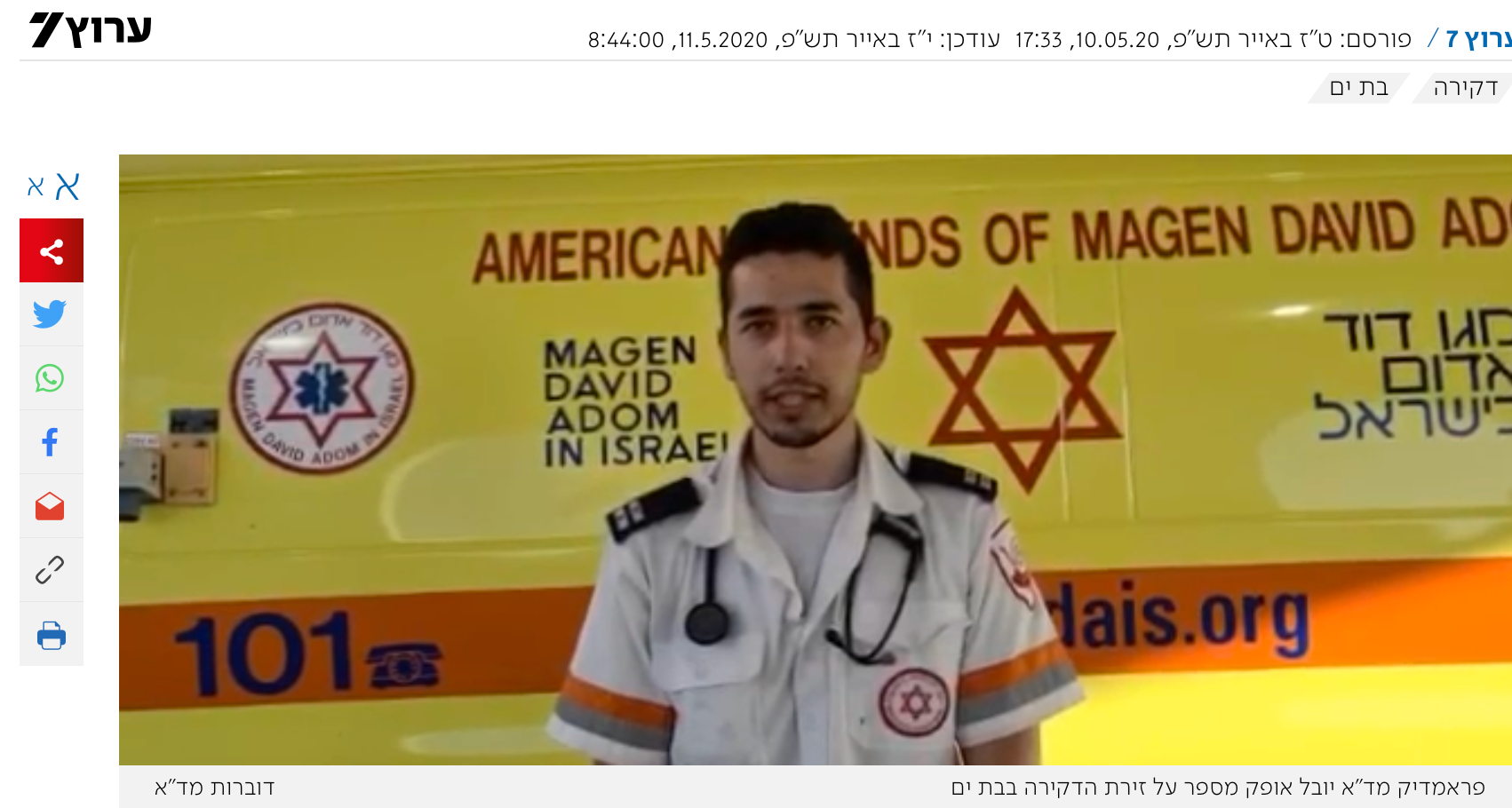 A person in a medical uniform stands in front of a yellow Magen David Adom ambulance featuring the organization's logo.