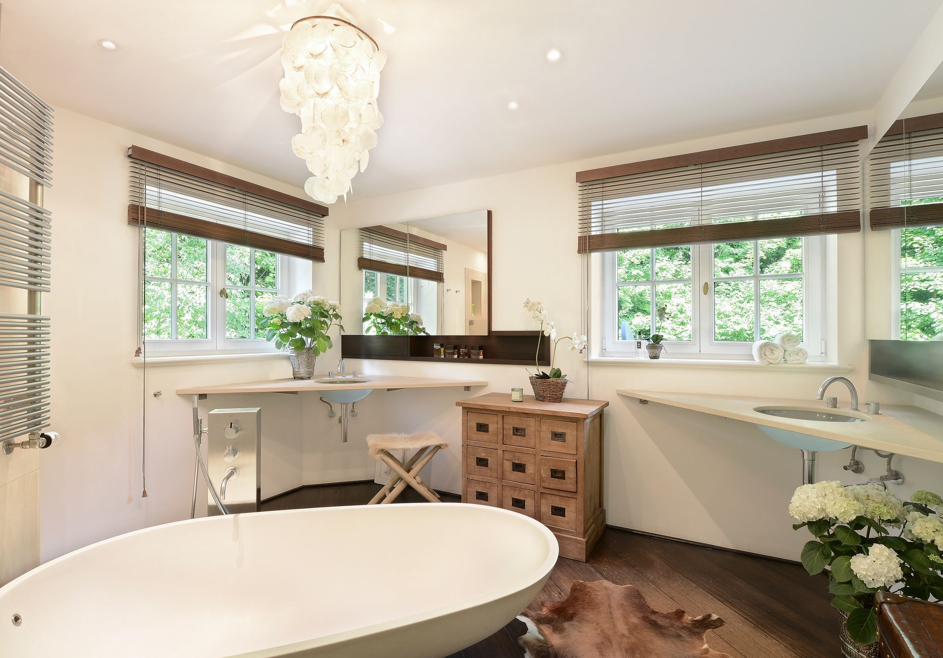 Luxurious bathroom with a freestanding tub, wood floors, and large windows.