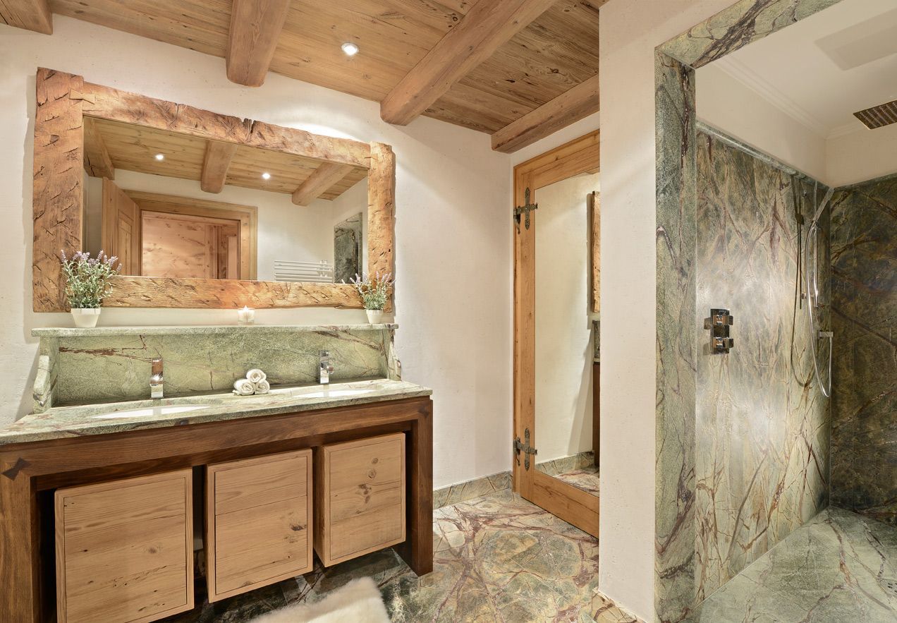 Rustic bathroom with wood beams, large mirror, wooden vanity, and marble shower.