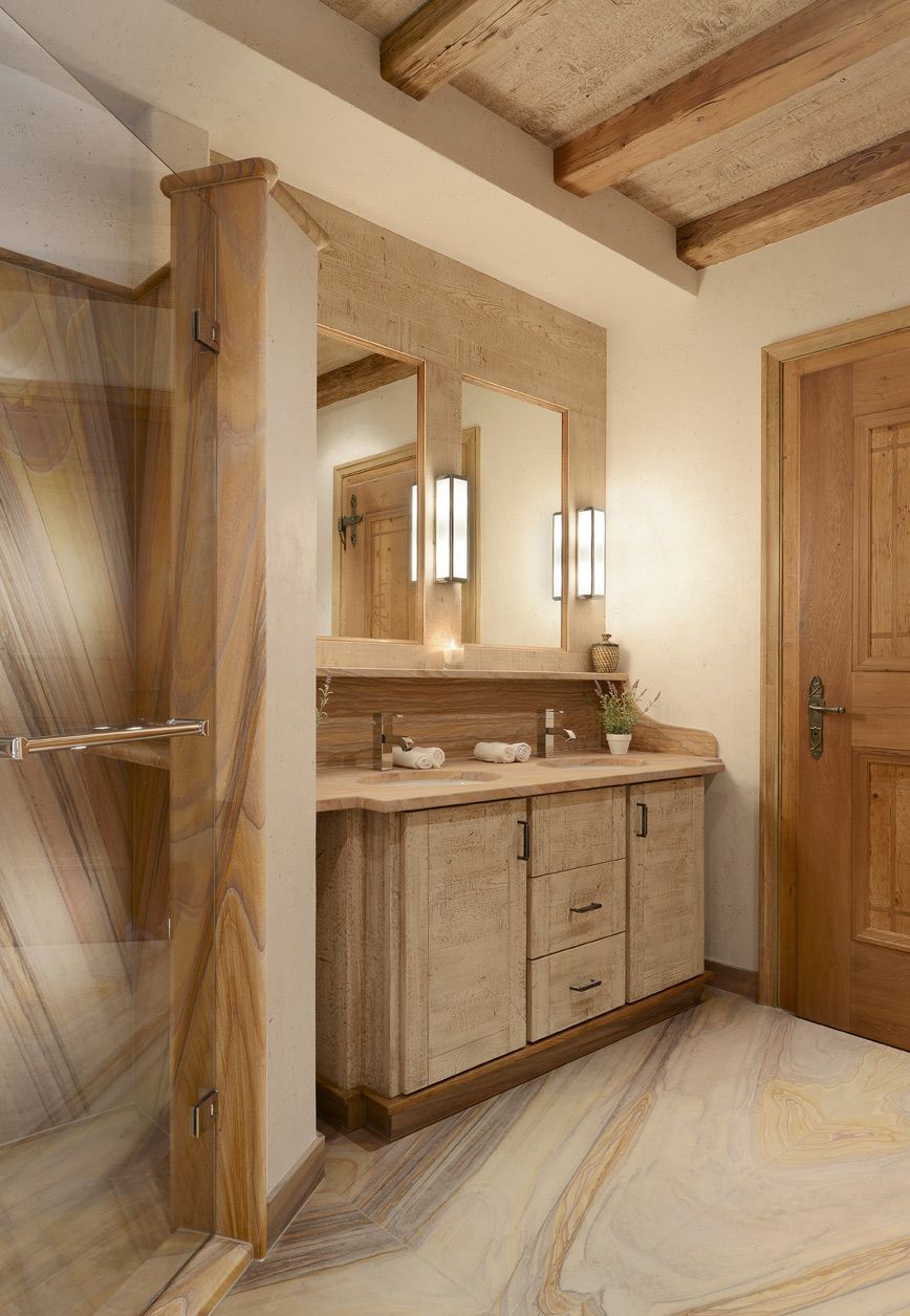 Wooden bathroom with vanity, mirrors, and shower stall. Beige and brown tones, wood ceiling.