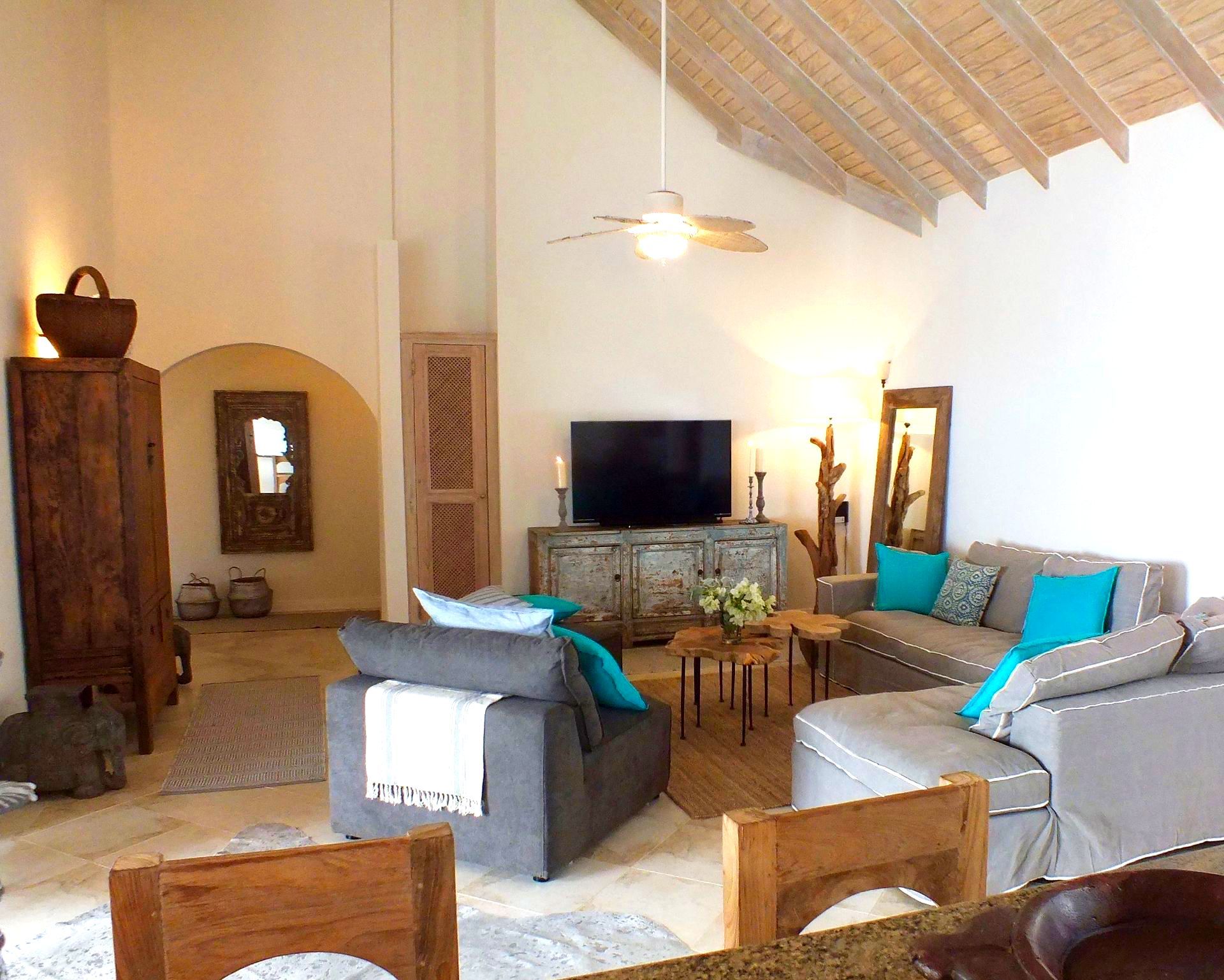 Living room with vaulted ceiling, sofas, TV, wood furniture, and arched doorways.