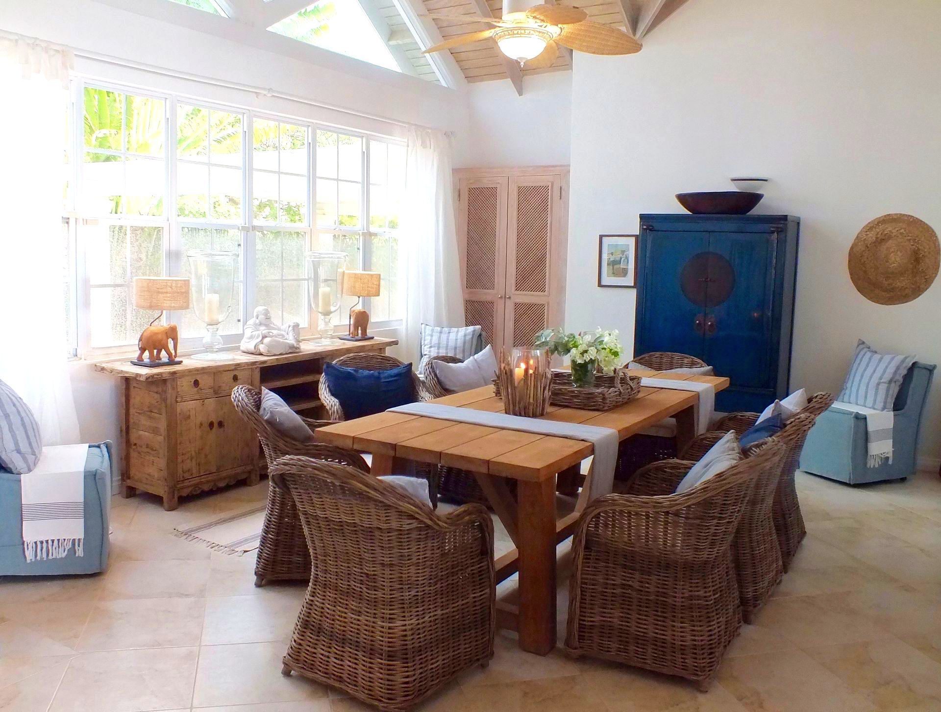 Dining room with wooden table, woven chairs, and coastal decor.