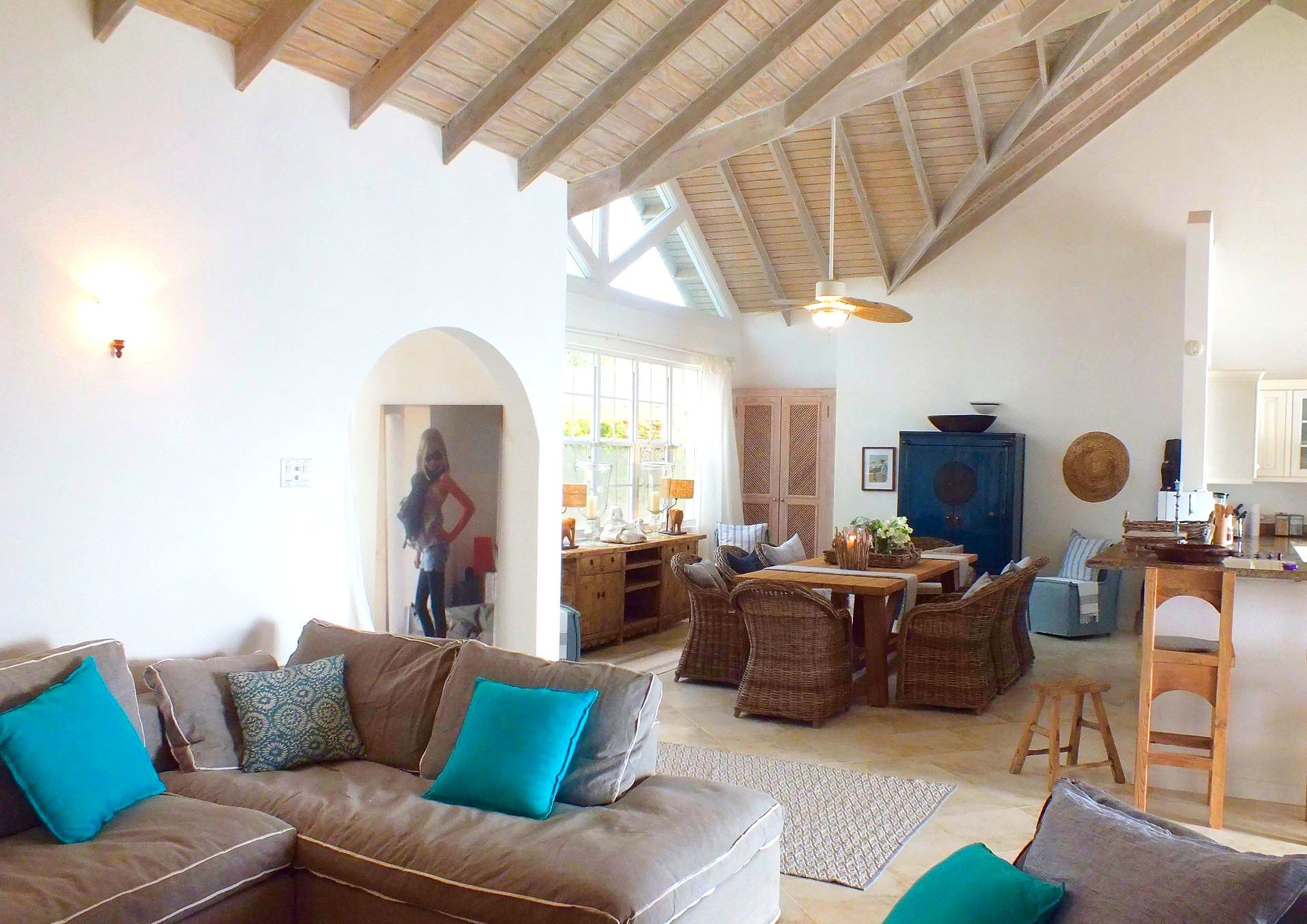 Open-plan living space with a sectional sofa, dining area, and exposed wooden beams.