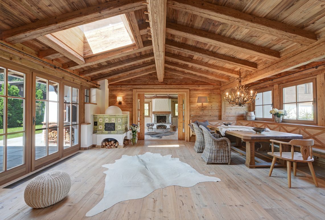 Wooden-paneled chalet interior with a fireplace, skylight, and dining area, featuring a cowhide rug.