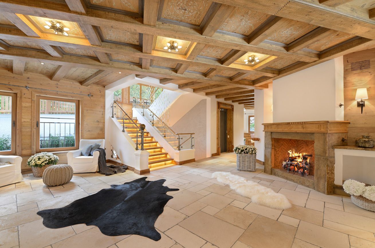Spacious, luxury lodge interior with wooden beams, fireplace, staircase, and natural light.