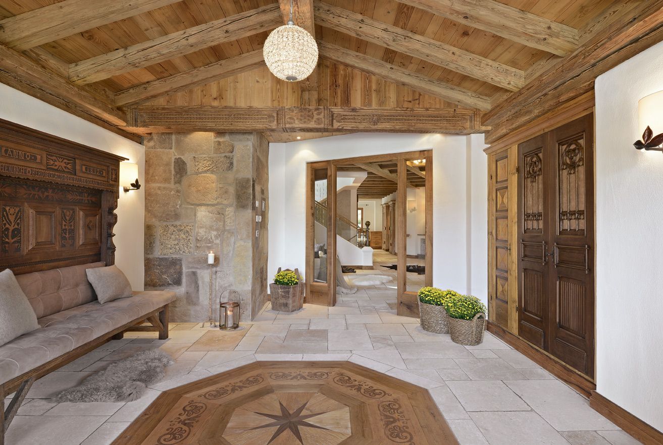 Entryway with wooden ceiling and doors, stone walls, and a wooden bench.