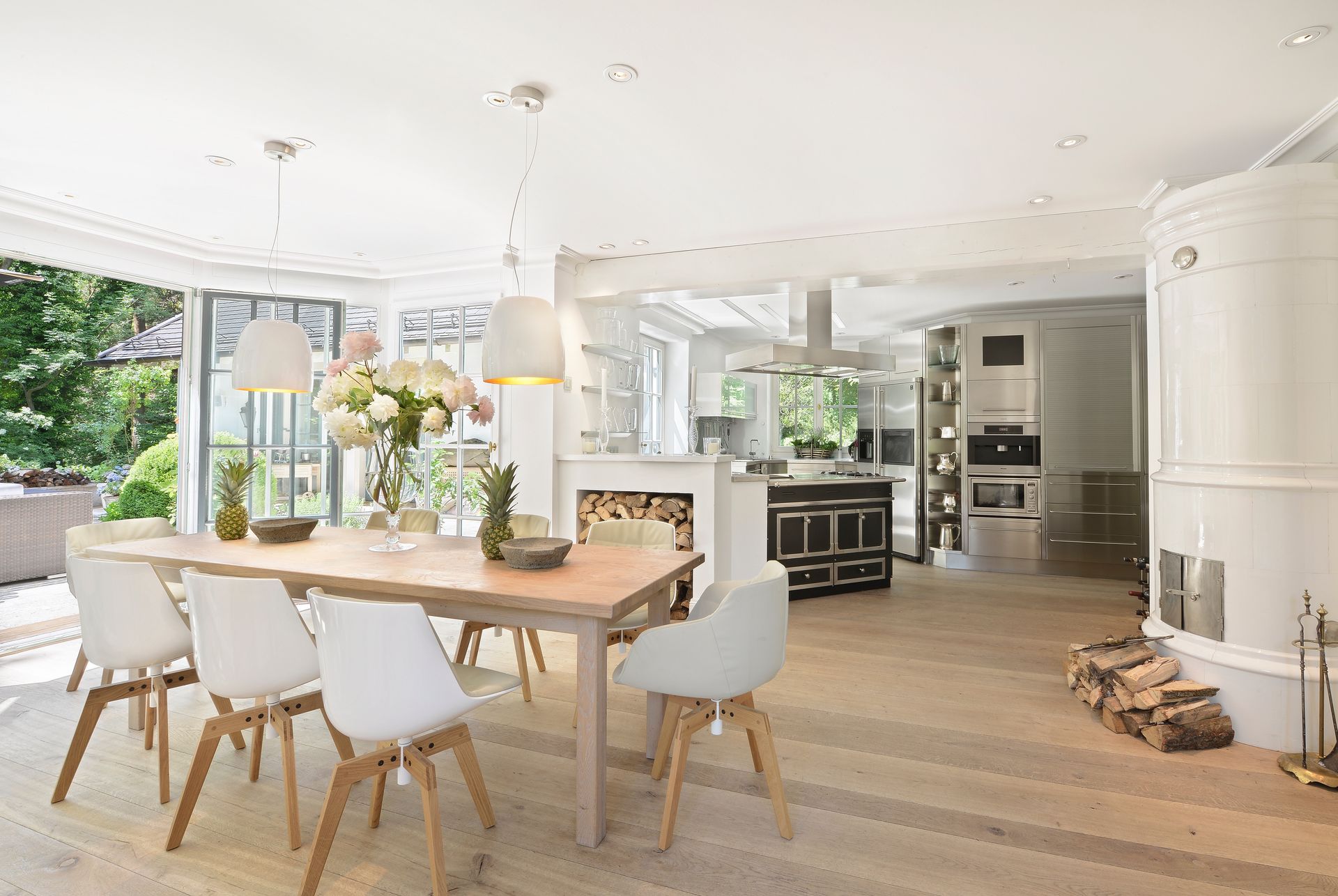 Bright, open-plan kitchen and dining area with wooden floors, table, chairs, and large white oven.